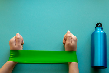 female hands doing exercise with fitness rubber bands on a blue background.home gym concept