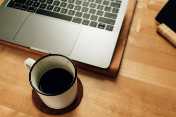 Coffee and laptop on wooden table in concept of work from home.