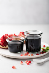 pomegranate sauce in a glass jar on a light background, place for text