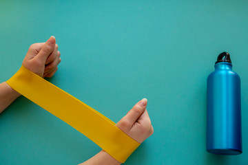 female hands doing exercise with fitness rubber bands on a blue background.home gym concept