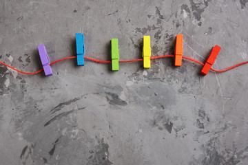 rainbow colored wooden clothespins and red hearts on grey concrete background.