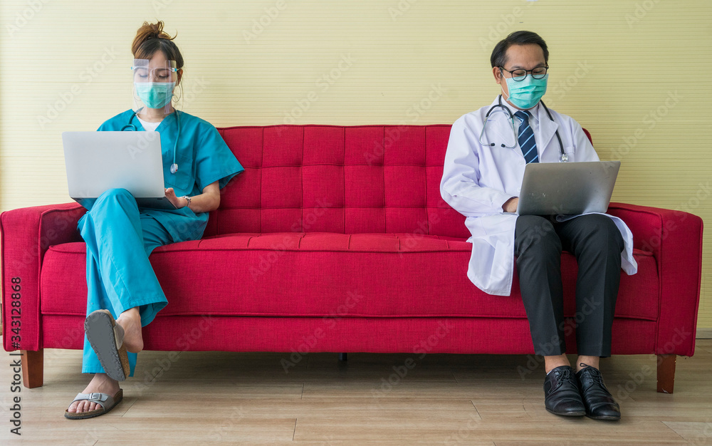 Wall mural asian doctors and male doctors wearing masks, sit and work, use a laptop, work to maintain social di