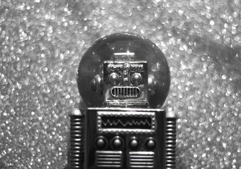Vintage snowball toy robot on the glistening silver bokeh background. Retro toys minimal concept....