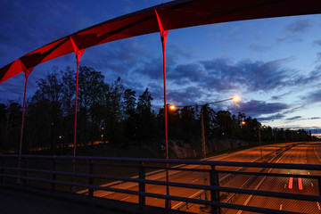 Fototapeta na wymiar Stockholm, Sweden A red-colored pedestrian bridge over the E4 highway at Rotsunda.
