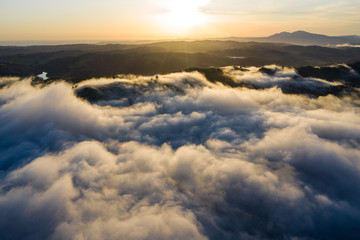 Sunrise illuminates the marine layer covering hills and valleys in California's Bay Area. The foggy marine layer is a climatic phenomenon that is an almost daily occurrence in this region.
