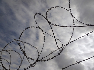 Barbed wire under twilight cloudy gray sky. Chain link fence.