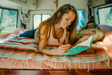 young woman lying on the bed with a journal