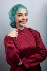 dentista con cuffietta verde in testa e camice rosso ci mostra scherzosamente come si controlla un...