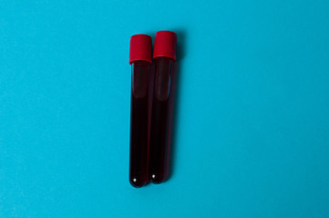 Two test tubes with blood isolate on blue background. The concept of medicine, the fight against viruses and bacteria, diseases