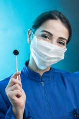 Dentista donna con mascherina chirurgica e camice blu mostra gli strumenti di lavoro, isolata su...
