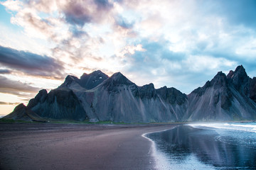 Fototapeta premium Scenic landscape with most breathtaking mountains Vestrahorn on the Stokksnes peninsula with the waves of the bay at sunset in Iceland. Exotic countries. Amazing places.