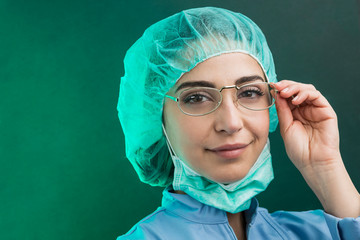 Chirurgo donna  vestita con camice,  cuffietta e mascherina chirurgica , guarda seria e si tocca...
