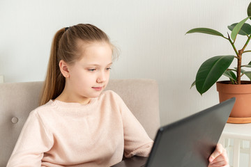 School girl studying at home with laptop notebook and listens to an online lesson. Home education, quarantine concept