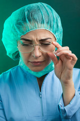 Medico donna con occhiali  vestita con camice,  cuffietta e mascherina chirurgica guarda il...