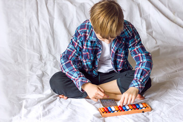  A boy a schoolboy does tasks on mental arithmetic on an abacus at home, distance online learning during coronavirus quarantine, additional mental development