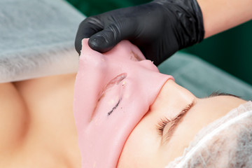 Obraz na płótnie Canvas Process of removing facial alginate mask from face of woman close up.