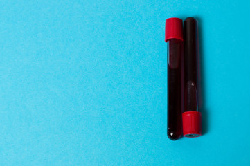 Two test tubes with blood isolate on blue background. The concept of medicine, the fight against viruses and bacteria, diseases