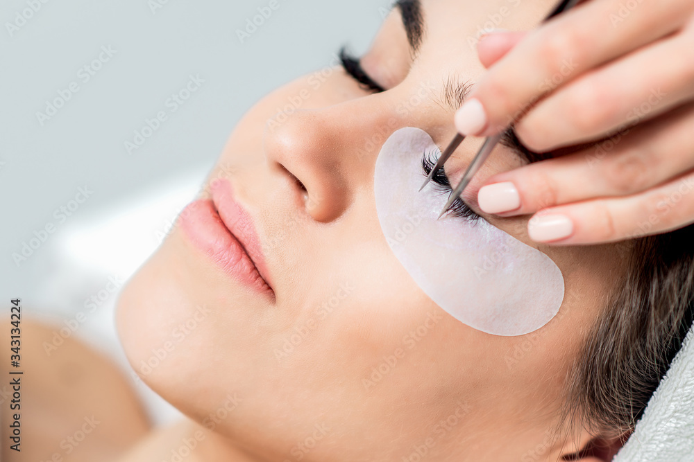 Wall mural woman receiving eyelash extension procedure, close up.