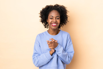 Young African American woman isolated on beige background laughing