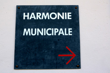 Panneau avec l'inscription Harmonie Municipale et une flèche rouge indiquant le sens de la salle de répétition de musique.