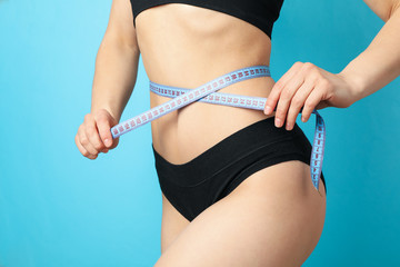 Woman measuring her waist on blue background. Healthy lifestyle