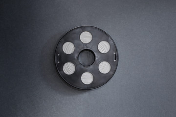 Black coil with white plastic, 3D printing filament reel for 3d printers  is on a black background.