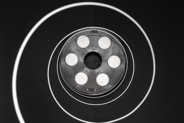 Black coil with white plastic, 3D printing filament reel for 3d printers  is on a black background.