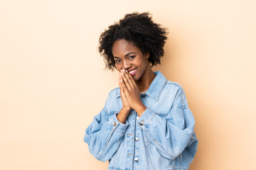 Young African American woman isolated on beige background keeps palm together. Person asks for something