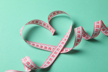 Measuring tape in the form of heart on mint background