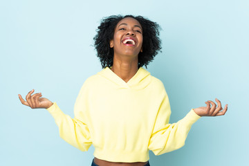 Young African American woman isolated on blue background smiling a lot