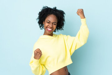 Young African American woman isolated on blue background celebrating a victory