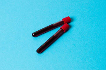 Two test tubes with blood isolate on blue background. The concept of medicine, the fight against viruses and bacteria, diseases