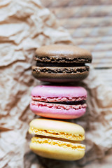 Trois macarons saveur citron framboise et chocolat posés sur du papier brun