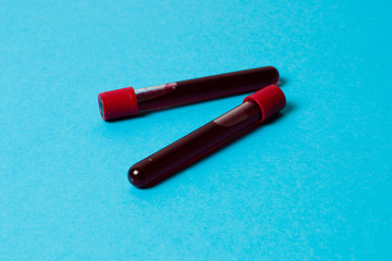 Two test tubes with blood isolate on blue background. The concept of medicine, the fight against viruses and bacteria, diseases