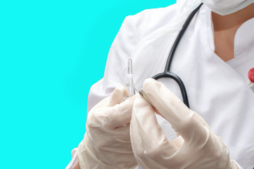 A young woman doctor in a medical coat and gloves opens an ampoule with medicine for injection. Close up, isolated blue background.
