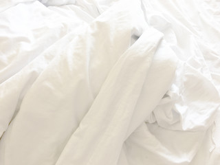 wrinkle messy blanket and white pillow in bedroom after waking up in the morning, from sleeping in a long night, details of duvet and blanket, an unmade bed in hotel bedroom with white blanket