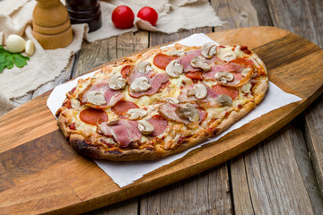 Pinsa with bacon and mushrooms, rome pizza on wooden table