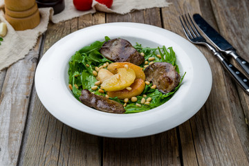 Salad with chicken liver on wooden table