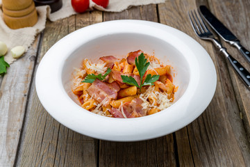 Penne with bacon and Parmesan on wooden table