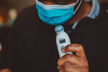 African american man using a temporal thermometer to record his temperature by running it across...