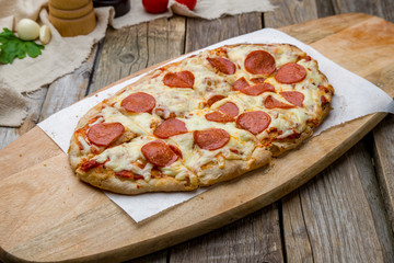 Pepperoni pizza on Roman dough pinsa on wooden table