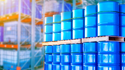 Blue barrels are stored in several levels. Concept - oil storage containers. Metal barrels as a symbol of oil production. Barrels in the warehouse of an oil refinery. Crude petroleum in stock.