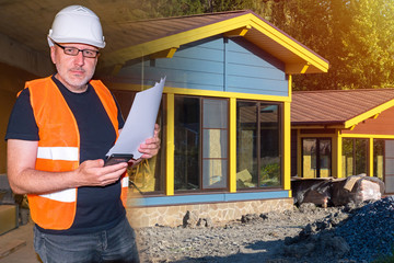 Builder near the cottages. Concept - construction of a country house. Construction of cottages in...