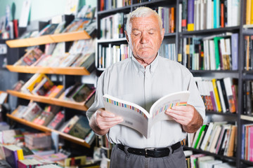 Mature man is choosing book for reading in free time