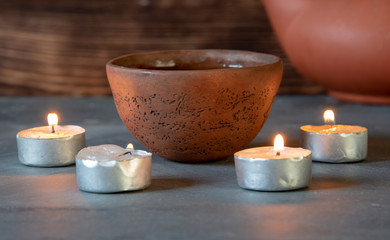 Obraz na płótnie Canvas A ceramic bowl with tea and burning candles on a gray tabletop.
