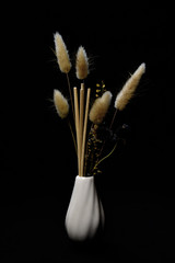 still-life. yellow spikelets in a white vase on a black background