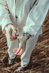 A ginger young woman standing at the lakeshore and rolling up sleeves on her white linen jacket. Handmade clothes. Natural fabrics. Slow Flow fashion. Travel and blog concept