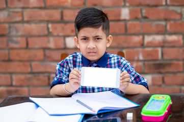 Little school kid learning from mobile , he is showing his mobile phone to the camera. Indian schools using latest technology for learning in schools.