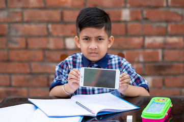 Little school kid learning from mobile , he is showing his mobile phone to the camera. Indian schools using latest technology for learning in schools.