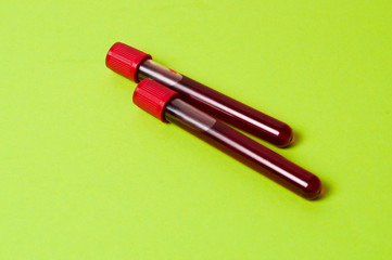 Two test tubes with blood isolate on green background. Concept medicine, the fight against viruses and bacteria, diseases